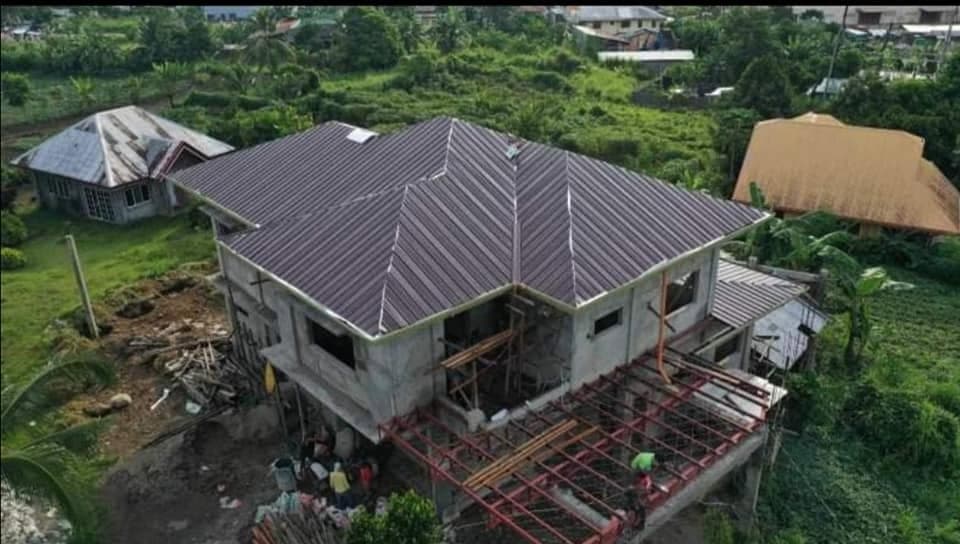 Aerial view of a new two-storey house with a maroon long-span roof