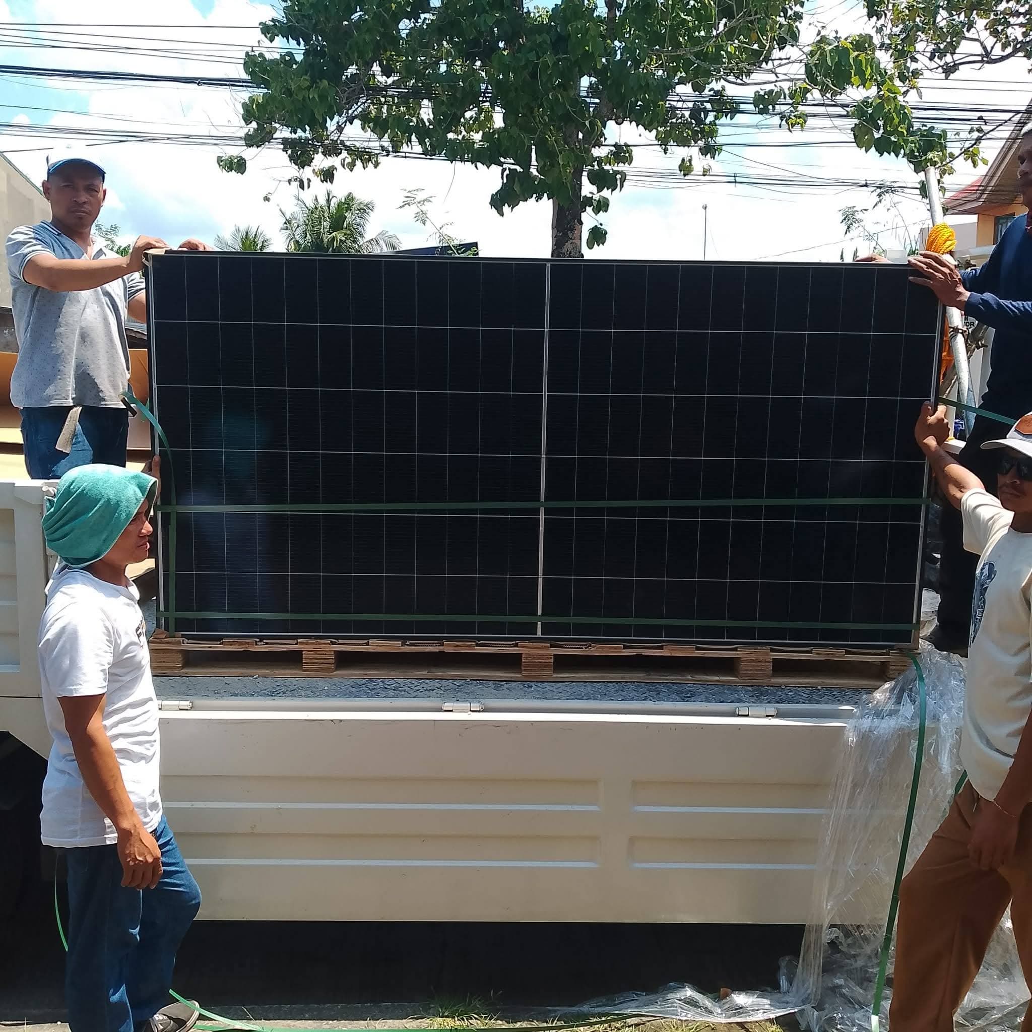 HL Bars crew unloading a pallet of 600W solar panels from a delivery truck